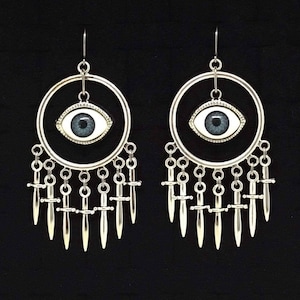 May include: A pair of silver earrings with a blue eye charm and a dangling fringe of silver swords.
