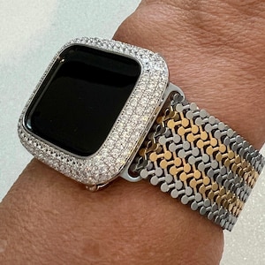 May include: A silver and gold metal watch band with a diamond encrusted watch face.