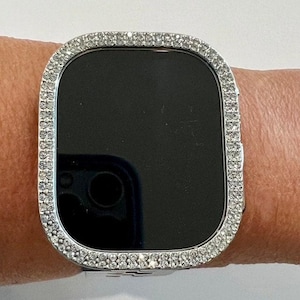 May include: A silver smartwatch with a diamond-encrusted bezel. The watch face is black and the band is silver.