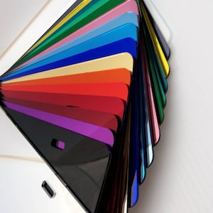 May include: A fan-shaped display of various colored acrylic sheets. The sheets are arranged in a rainbow pattern, with the darkest colors at the bottom and the lightest colors at the top. The sheets are all glossy and reflective.