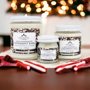 May include: Three glass jars of soy candles with white lids and labels. The labels are white with black text and a mountain logo. The candles are scented with "Old Fashioned Peppermint Bark" and come in three sizes: 1 ounce, 3 ounces, and 7 ounces.
