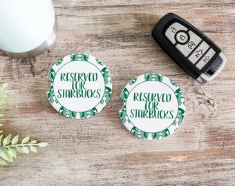 May include: Two white round car coasters with a green Starbucks logo border and the text "Reserved for Starbucks" in black.