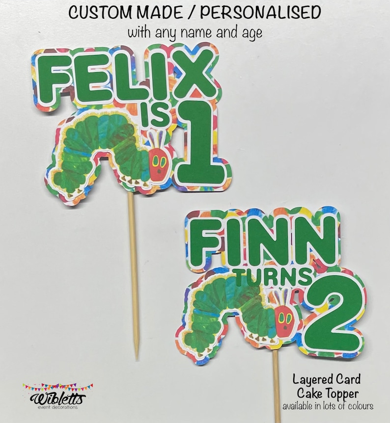May include: Two colorful layered card cake toppers featuring the Very Hungry Caterpillar. The first topper says "Felix is 1" and the second topper says "Finn turns 2".
