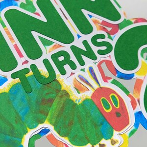 May include: Green paper cutouts of the words "Finn turns 2" with a colorful caterpillar illustration.