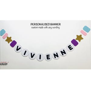 May include: A white banner with the name "VIVIENNE" spelled out in black letters. The banner is decorated with purple, pink, blue and gold stars and squares.