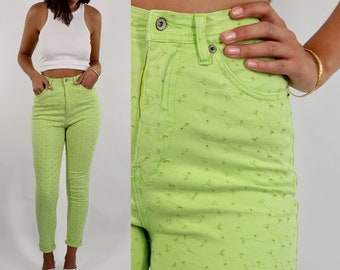 May include: A pair of light green high-waisted jeans with a floral pattern. The jeans are skinny fit and have a cuffed hem.