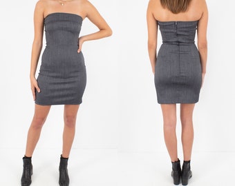 May include: A grey strapless mini dress with a fitted silhouette. The dress has a subtle herringbone pattern and a zip closure at the back.