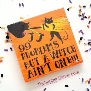 May include: Orange Halloween-themed napkins with a black cat riding a broom. The napkins have the text "99 Problems But A Witch Ain't One!!!" in black. The napkins are surrounded by colorful confetti.