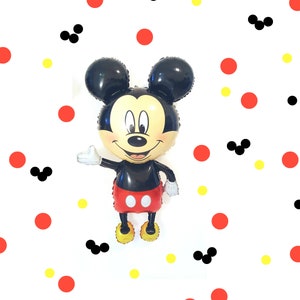 May include: A black and red Mickey Mouse balloon against a white background. The background is covered in red and yellow polka dots and black Mickey Mouse ears.