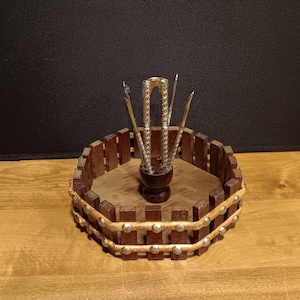 May include: A vintage nutcracker set with a wooden tray. The tray is hexagonal with a brown wooden fence design and silver studs. The set includes a nutcracker and picks, all with ornate metal detailing.