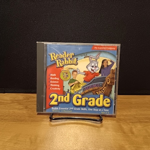 May include: A Reader Rabbit 2nd Grade CD-ROM. The cover features a cartoon rabbit, children, and the text "2nd Grade." It lists subjects like math, reading, and science. The CD-ROM is designed for Windows and Macintosh and is for ages 6-8.