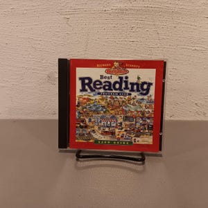May include: A CD case featuring the cover of "Richard Scarry's Best Reading Program Ever." The cover is red with the title in large blue letters. The image shows a detailed illustration of a town scene with various characters and buildings.