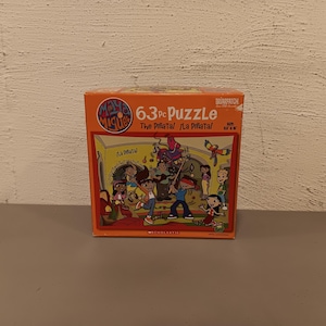 May include: A boxed 63-piece puzzle featuring the characters from Maya & Miguel. The box is orange with the title "The Piñata!" and illustrations of the characters. The puzzle is from Briarpatch and Scholastic.