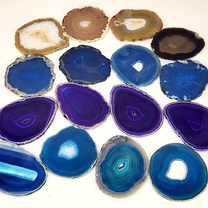 May include: A collection of polished agate slices in various shades of blue, purple, brown, and white. Each slice has a unique pattern and shape, with concentric rings and natural formations. These decorative stones are ideal for home decor or craft projects.