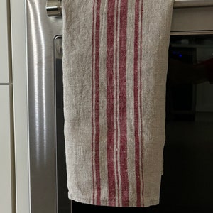 May include: A striped kitchen towel with red and beige stripes hanging on a silver oven door handle.
