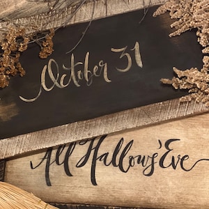 May include: Two rustic wooden signs with the words "October 31" and "All Hallows' Eve" in elegant script. The signs are framed with weathered wood and adorned with dried floral accents, evoking a vintage Halloween theme.