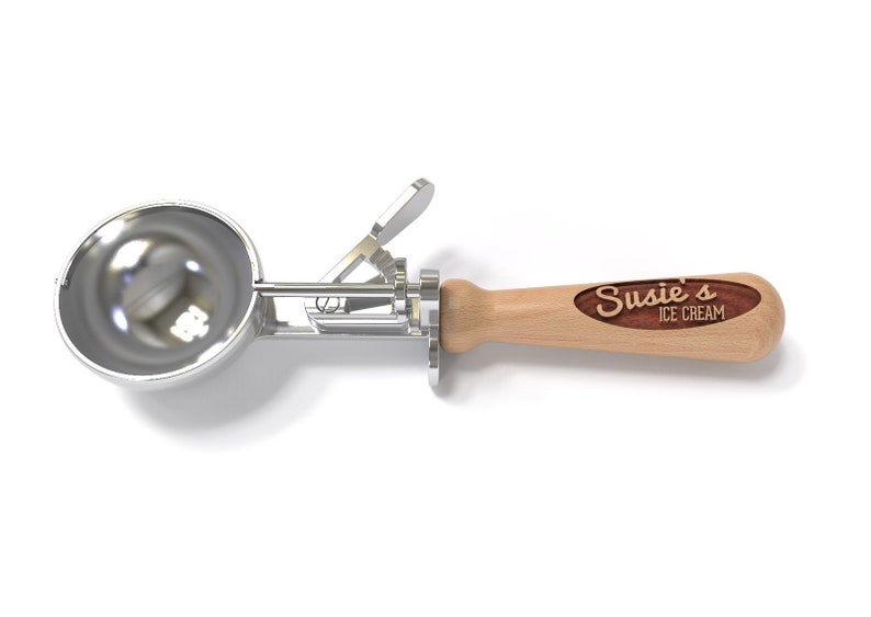 May include: A silver ice cream scoop with a wooden handle. The handle has a brown oval inlay with the text "Susie's Ice Cream" engraved in white.