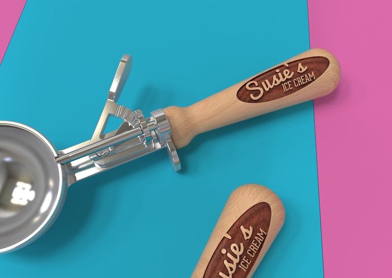 May include: Two silver ice cream scoops with wooden handles. The handles are engraved with the text "Susie's Ice Cream".