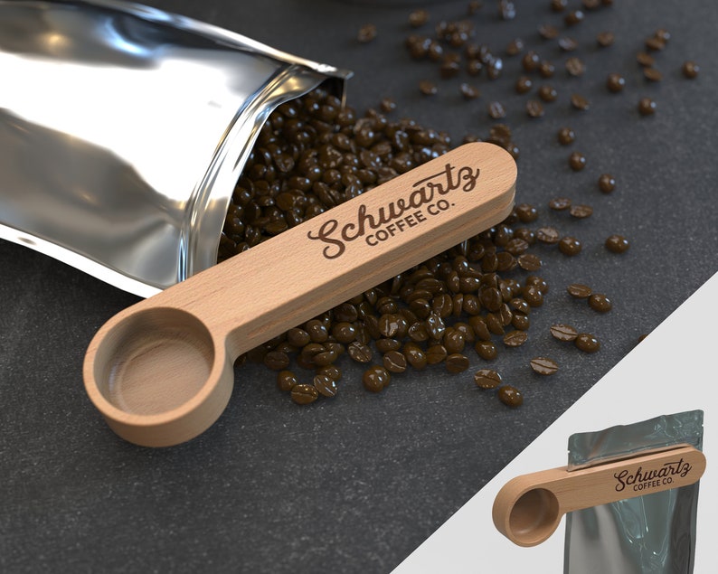 May include: A wooden coffee scoop with the text "Schwartz Coffee Co." engraved on the handle. The scoop is sitting on a pile of coffee beans.