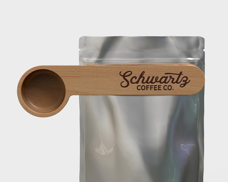 May include: A wooden scoop with a handle that clips onto a bag of coffee. The handle has the text "Schwartz Coffee Co." engraved on it.