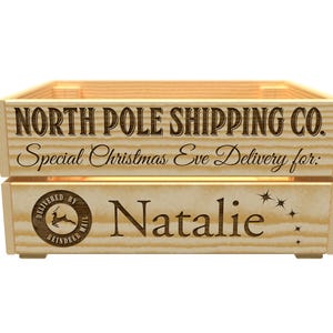 May include: A wooden crate with the text "NORTH POLE SHIPPING CO." and "Special Christmas Eve Delivery for:" is displayed. The name "Natalie" is engraved on the crate, along with a reindeer mail logo and star accents.