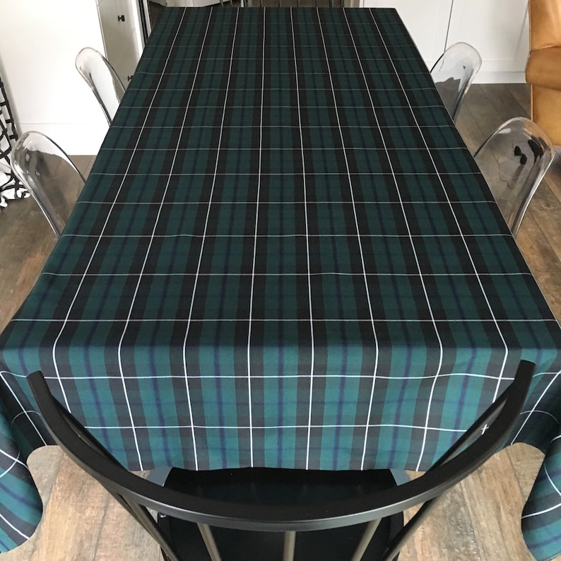 May include: A green and white plaid tablecloth with a black and white checkered pattern. The tablecloth is laid out on a table with chairs around it.