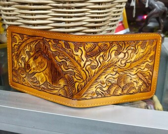 May include: A brown leather wallet with an intricate carved design of a horse and floral patterns.