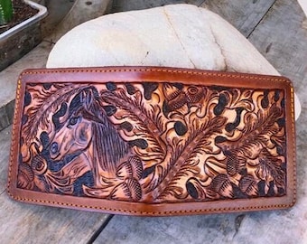 May include: A brown leather wallet with a tooled design of a horse's head and floral patterns.
