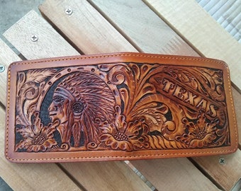 May include: A brown leather wallet with intricate tooled designs featuring a Native American head, floral patterns, and the word "TEXAS".