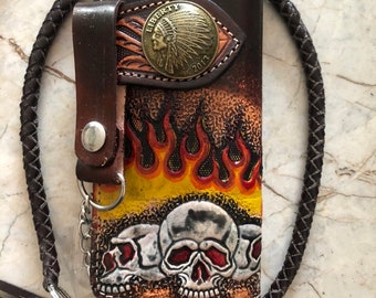 Könnte beinhalten: Eine braune Ledergeldbörse mit einem geflochtenen Lederriemen und einer Metallkette. Die Geldbörse hat ein Totenkopf- und Flammenmotiv und eine Metallmünzbörse mit einem Bild eines indianischen Häuptlings und dem Wort "Liberty".