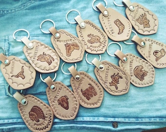May include: A collection of 12 leather keychains with various animal designs, including a horse, a bull, a buffalo, a deer, a bird, and a Native American headdress. Each keychain features the word "PUNCINE" or "PUNLINE" embossed on the leather.