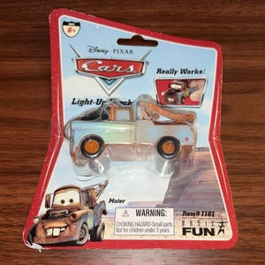 Può includere: Un camion giocattolo Mater di Disney Pixar Cars nella sua confezione originale. L'autocarro blu chiaro e marrone è in un blister rosso e bianco. La confezione include il testo "Cars", "Mater" e "Really Works!"