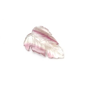 May include: A carved leaf pendant made of clear quartz with pink and purple hues. The leaf is carved with intricate details and has a smooth, polished finish.