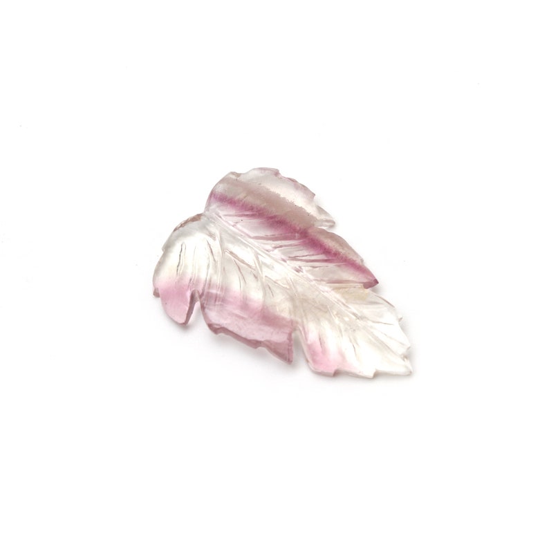 May include: A carved leaf pendant made of clear quartz with pink and purple hues. The leaf is carved with intricate details and has a smooth, polished finish.