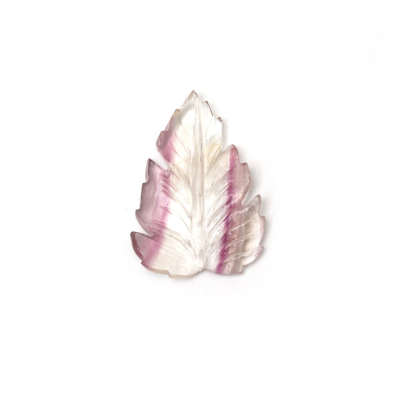 May include: A carved leaf pendant made of clear and purple fluorite. The leaf is detailed with veins and has a natural, organic shape.