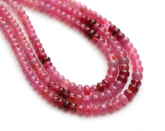 May include: A strand of pink and red gemstone beads. The beads are round and have a smooth, polished finish.