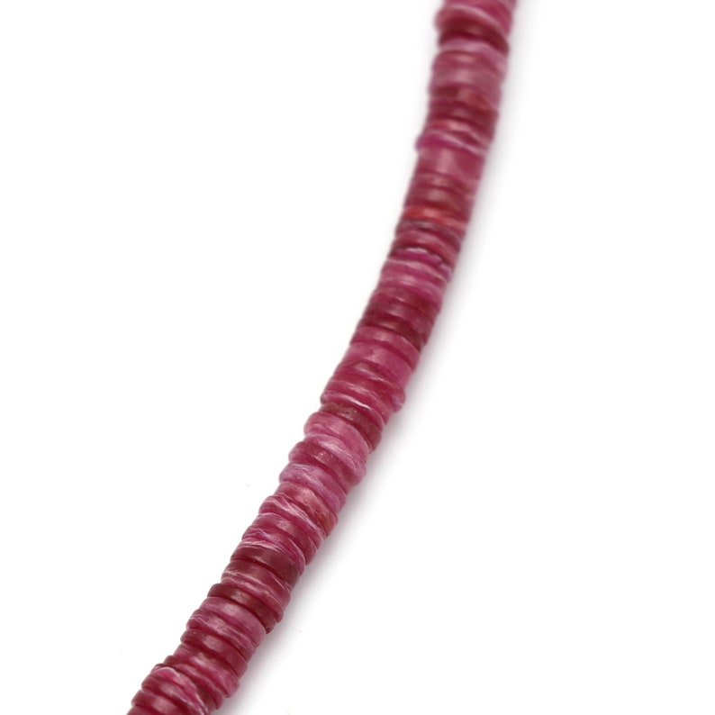 May include: A strand of pink gemstone beads, each bead is a flat, round disc with a slightly textured surface.