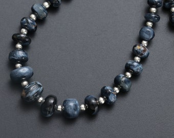 May include: A necklace made of dark blue and silver beads. The beads are oval shaped and have a marbled pattern.