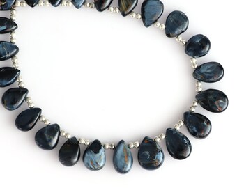 May include: A strand of blue tiger's eye gemstone beads in a teardrop shape. The beads are strung on a silver wire.