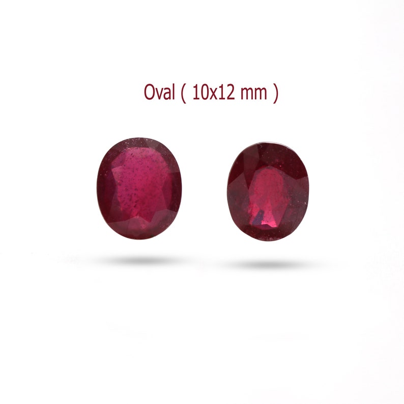 May include: Two oval-shaped, deep red gemstones, each measuring 10x12 mm.  Oval ( 10x12 mm ) is written above the gemstones.
