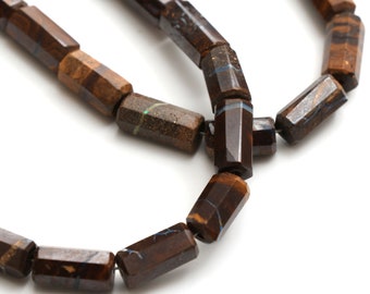 May include: A strand of brown and black gemstone beads with a faceted, rectangular shape. The beads have a subtle iridescent sheen.