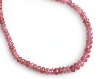 May include: A strand of pink gemstone beads, each bead is faceted and has a slightly irregular shape. The beads are strung on a clear thread and are arranged in a circular pattern.