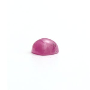 Puede incluir: Una piedra preciosa cabuj&oacute;n rosa con una superficie lisa y redondeada.