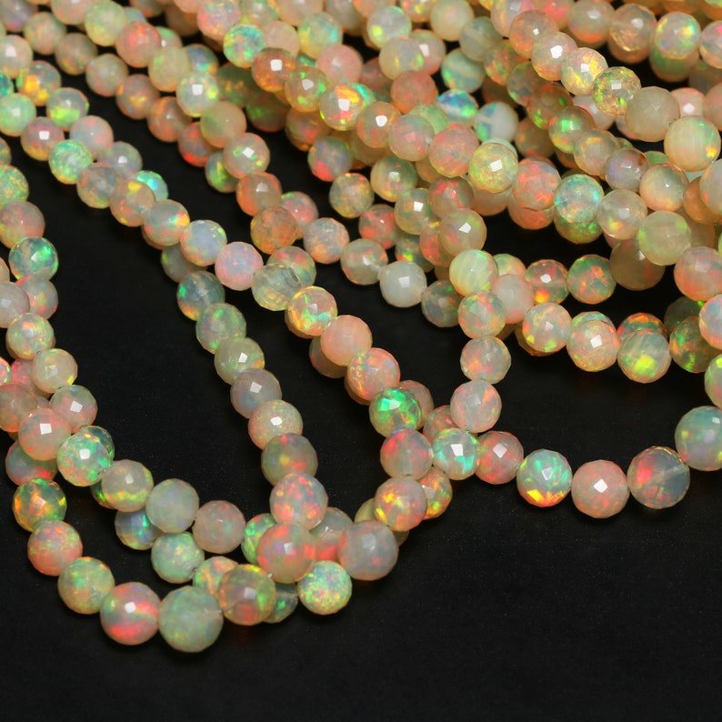 May include: A strand of iridescent opal beads, with a faceted finish, in shades of white, peach, and green. The beads are strung on a clear thread and are arranged in a loose, flowing pattern.