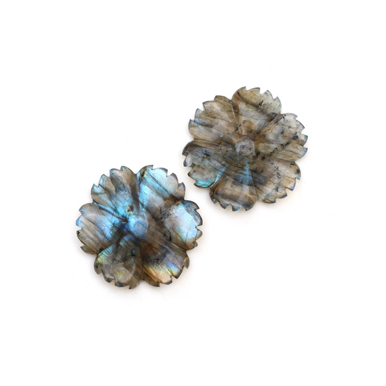 May include: Two iridescent blue and gray labradorite flower-shaped pendants. The pendants have a carved flower design with a center hole.