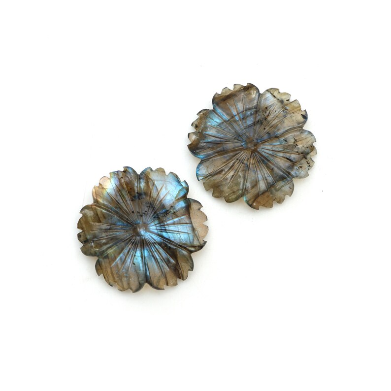 May include: Two iridescent blue and brown labradorite gemstone flower carvings. The flowers have a starburst pattern in the center.