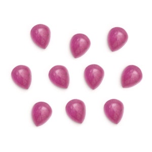 Puede incluir: Doce cabujones de color rosa en forma de l&aacute;grima, cada uno con un tono de rosa ligeramente diferente, est&aacute;n dispuestos en un patr&oacute;n disperso sobre un fondo blanco.