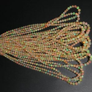 May include: A strand of iridescent opal beads in shades of peach, yellow, and green. The beads are faceted and have a smooth, polished finish.