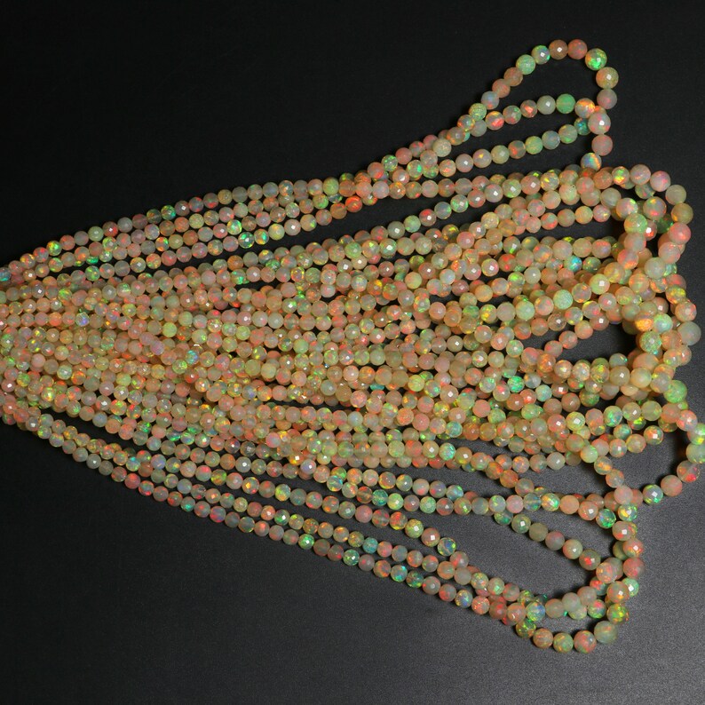 May include: A strand of iridescent opal beads in shades of peach, yellow, and green. The beads are faceted and have a smooth, polished finish.