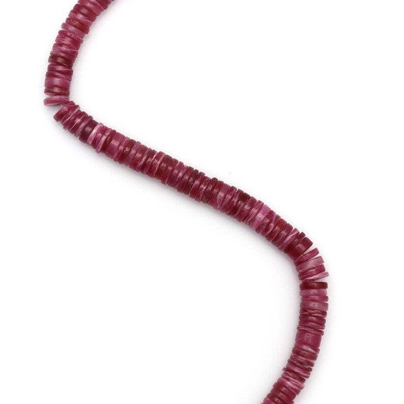 May include: A strand of pink and white round beads, made of natural materials, strung together on a thin cord.